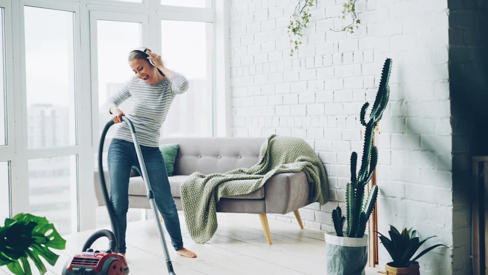 Cleaner vacuuming a bright living room