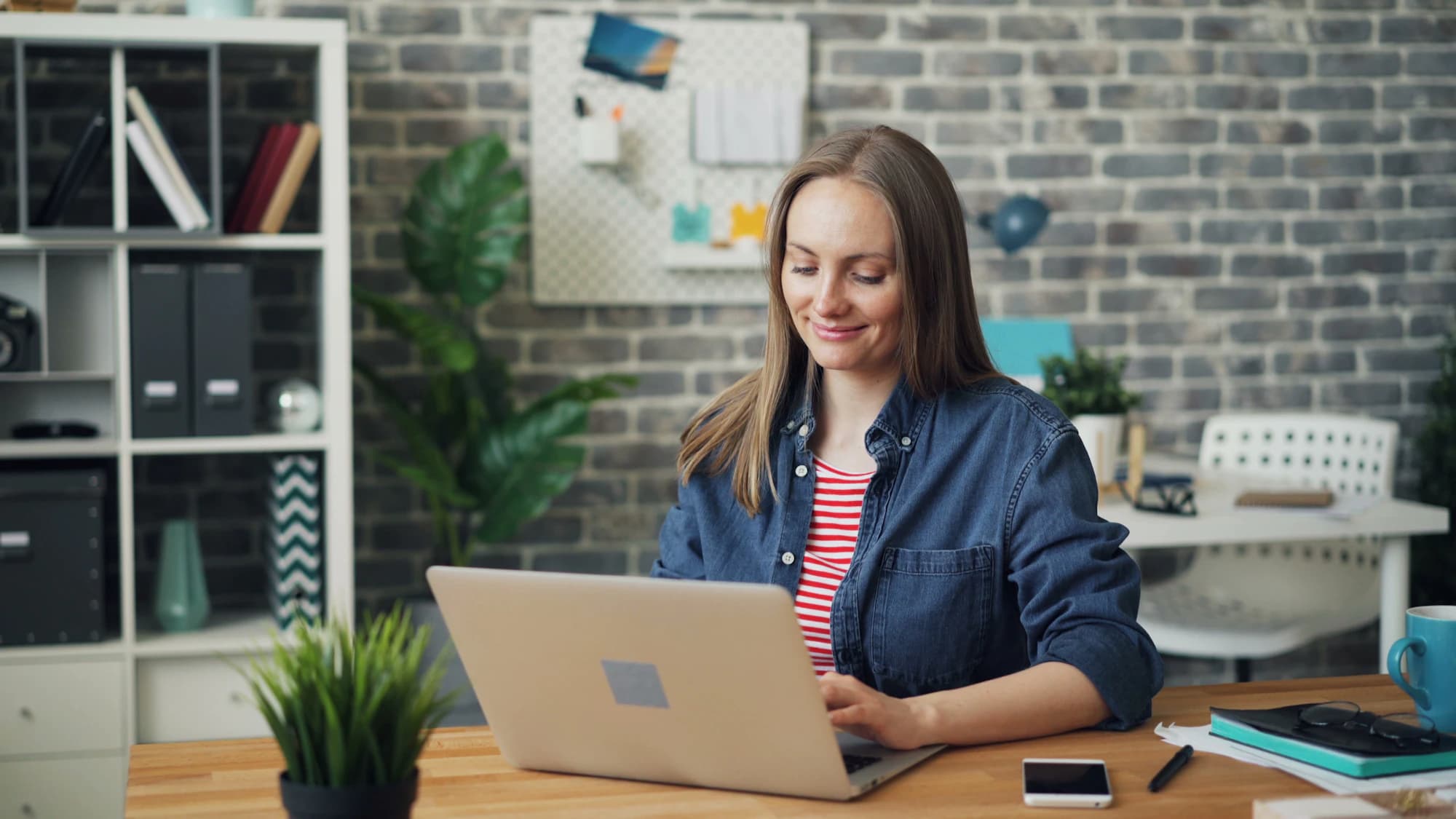 Smiling virtual assistant working on a laptop at her desk